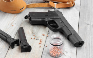 Air pistol, two clips, holster and balls for shooting at a wooden table.