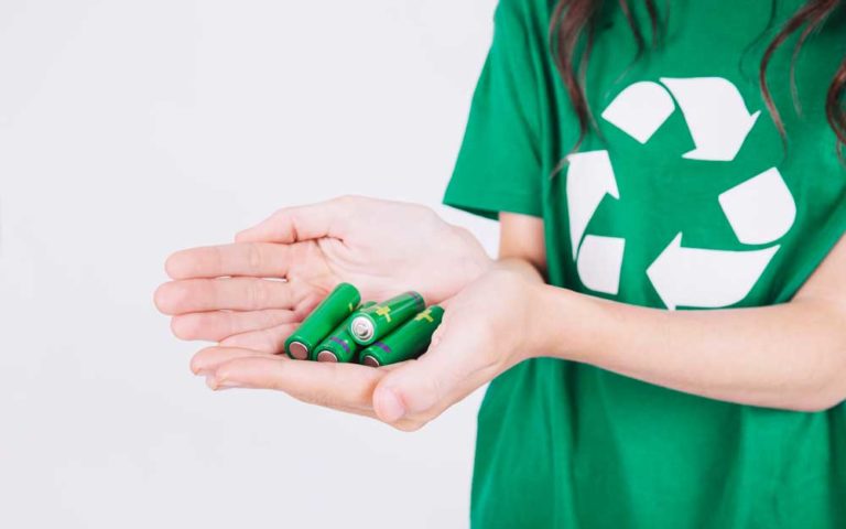 Close-up of a woman's hand holding green batteries