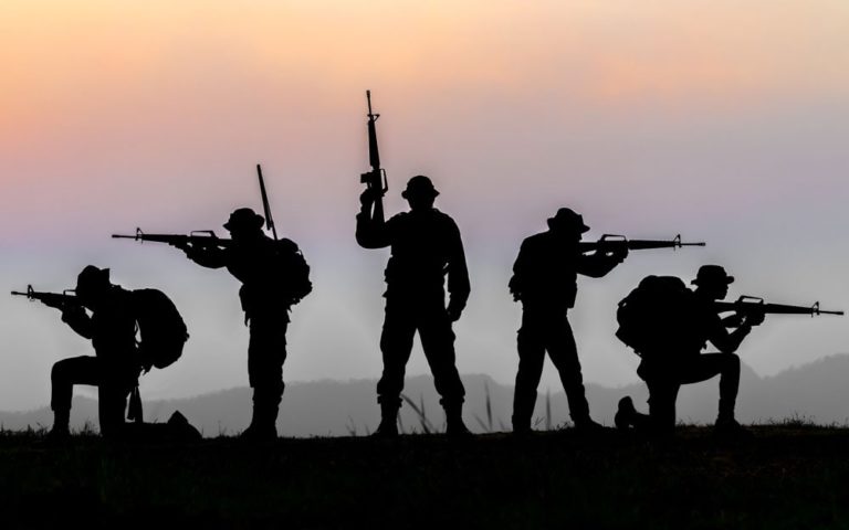 Military or soldier silhouettes on sunset sky background